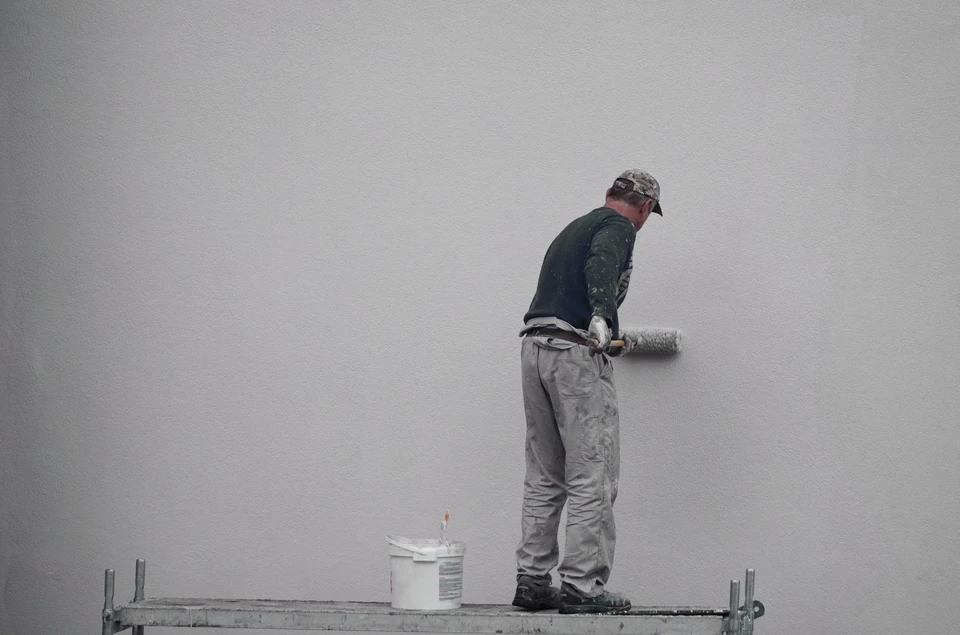Peintre professionnel appliquant de la peinture au rouleau sur un mur extérieur